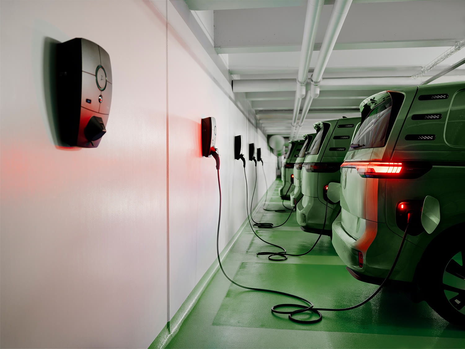 Fileira de carregadores de parede numa garagem coletiva, com vans elétricas carregando